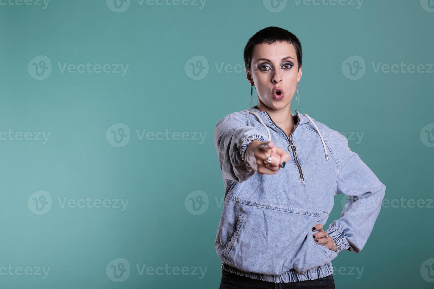 Displeased sad woman pointing index finger in front of camera screaming during studio shot on isolated background. Upset nervous female having mental breakdown, disappointment expression photo