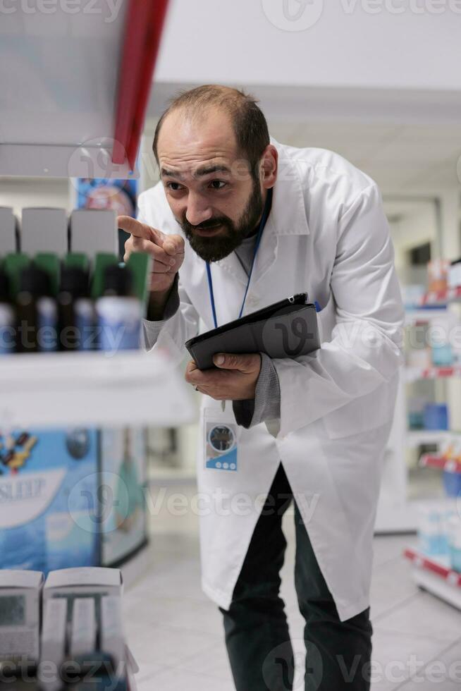 farmacia trabajador haciendo medicamentos inventario comprobación drogas paquetes mecanografía bar código en tableta computadora. farmacéutico es un entrenado profesional quien es responsable para dispensación medicación en farmacia foto