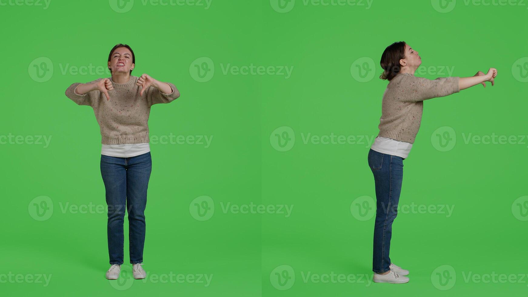 Female model showing thumbs down negative sign on camera, doing disapproval and bad symbol. Confident woman expressing disagreement with dislike gesture over full body greenscreen. photo