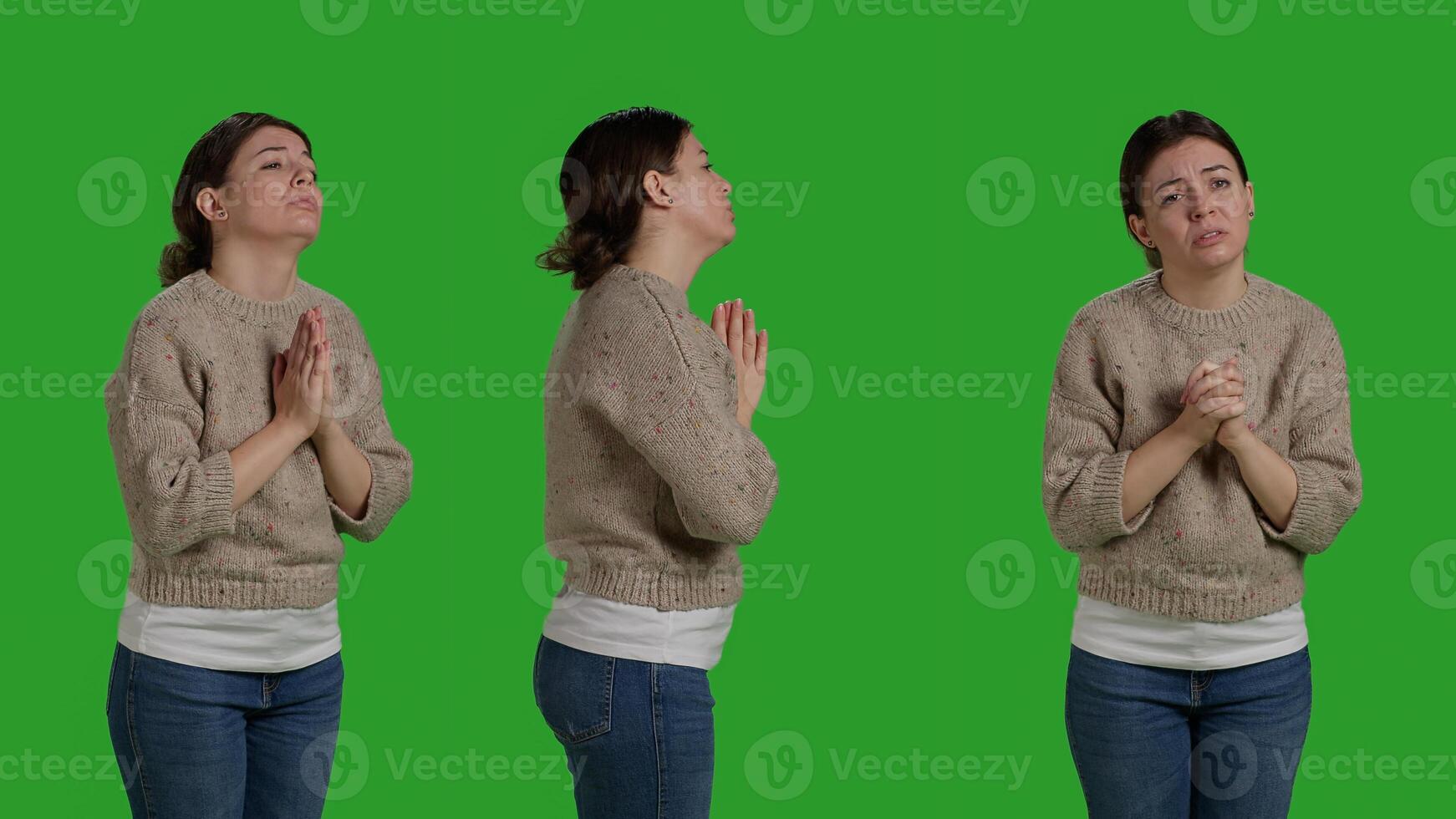Religious spiritual girl posing with prayer hands sign in studio, praying to god to receive luck and fortune. Young adult expressing spirituality and belief, standing in silence on greenscreen. photo
