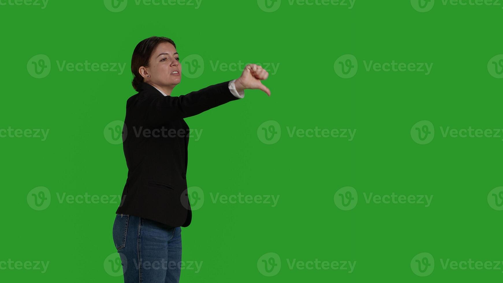 Side view of corporate employee giving thumbs down symbol in studio, doing dislike and negative bad gesture. Businesswoman with office suit expressing disapproval and disagreement on camera. photo