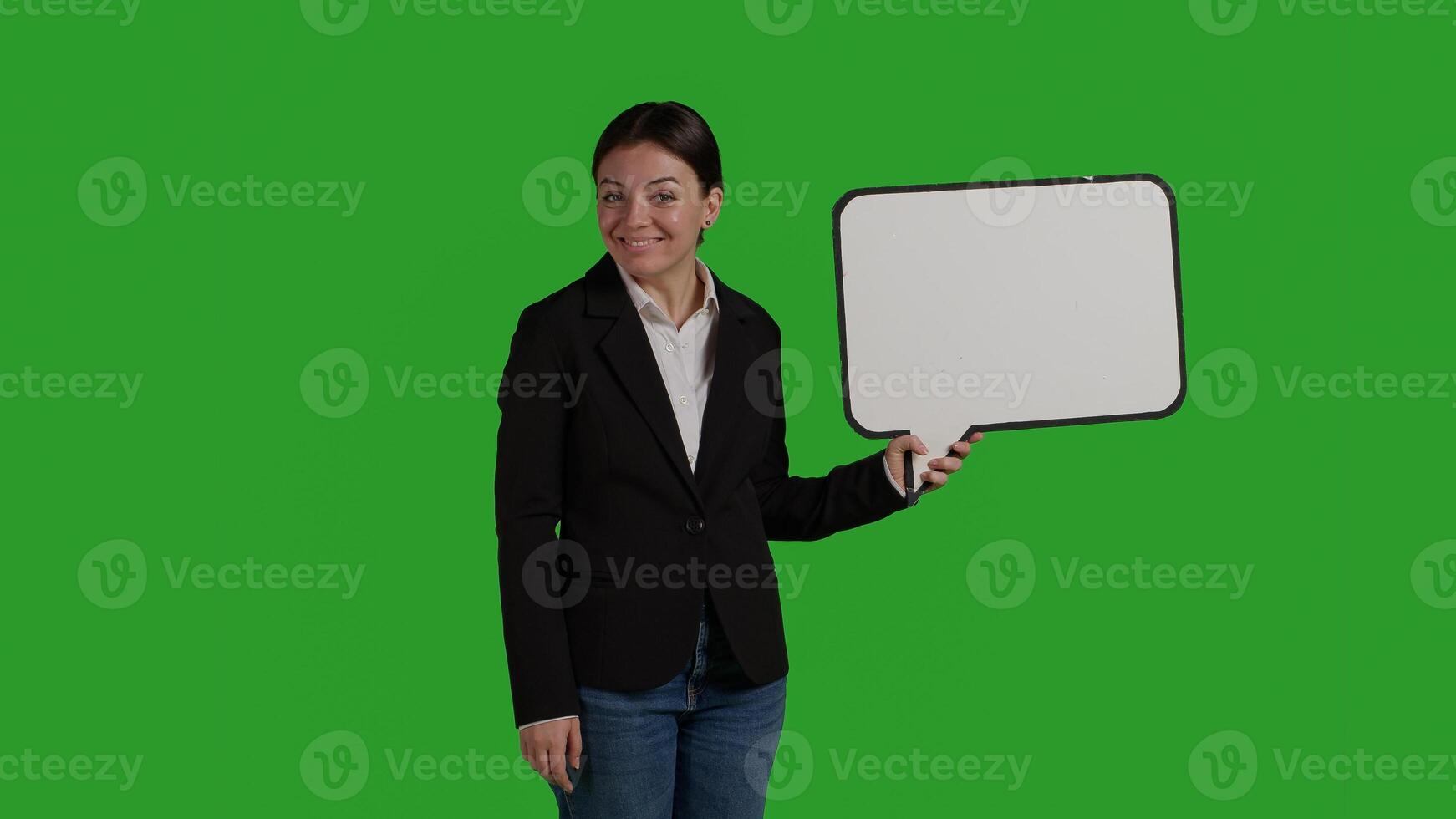 Front view of business manager holding speech bubble on camera, showing isolated cardboard icon over greenscreen backdrop. Woman in suit using carton board with blank copyspace in studio. photo