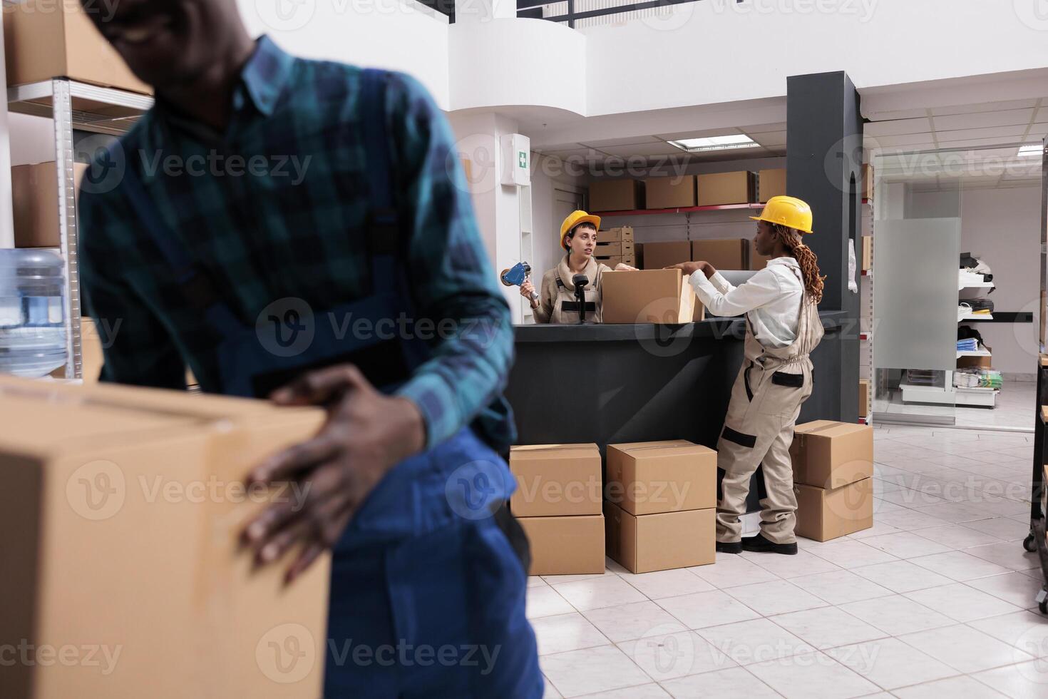 Delivery department warehouse coworkers taping parcel with adhesive at table. Mail sorting center employees closing cardboard box and carrying heavy container at post office storehouse photo