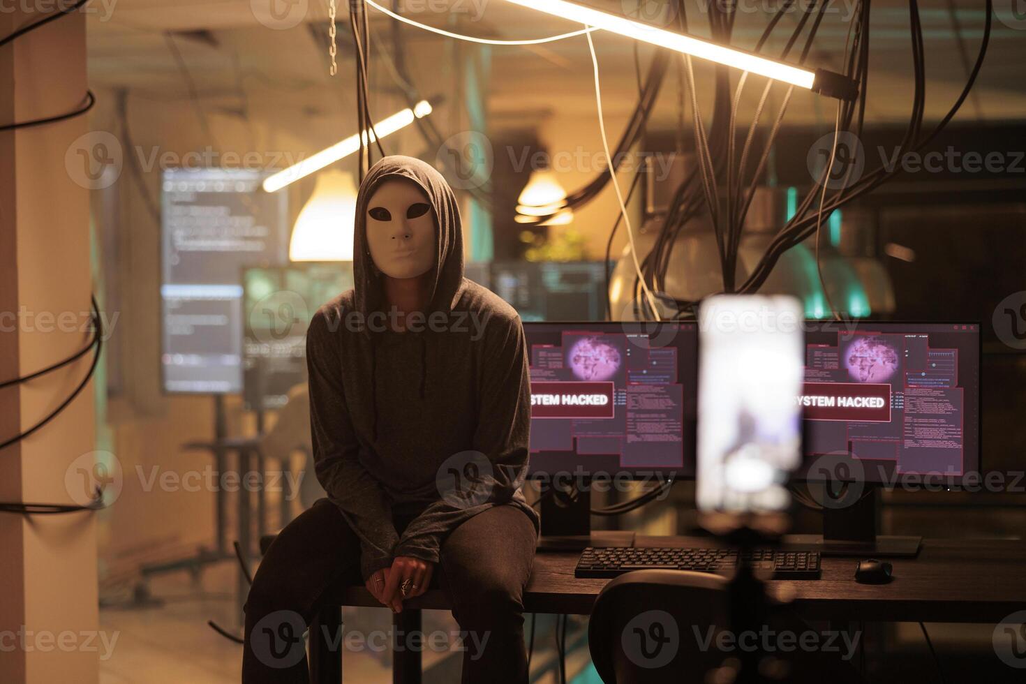 Young hacker with anonymous mask attacking computer server, committing cybercrime. Database system hacking, information phishing, system malware programming, cyber criminal working at night. photo
