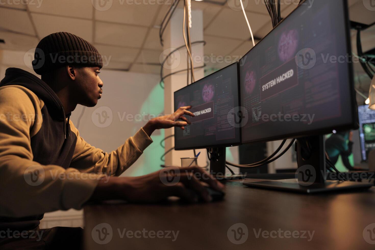African american hacker planting trojan virus to steal data, looking at montors to create malware. Person working on spyware to break into government system and network, cyberattack. photo