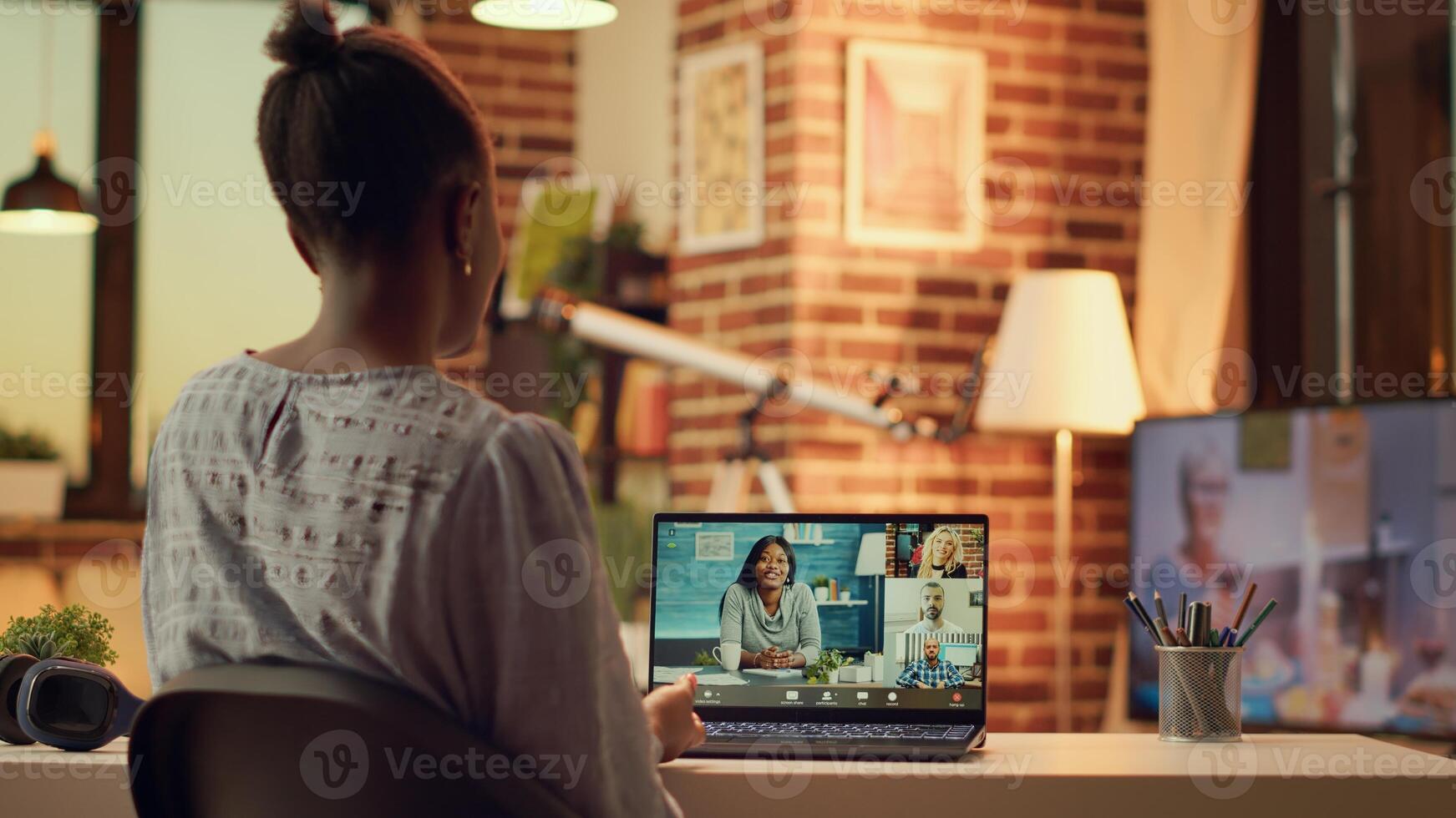 Freelancer on videocall with contractors using webcam to discuss remotely about new project tasks and deadlines. African american woman meets with clients, teleworking from home. Handheld shot. photo