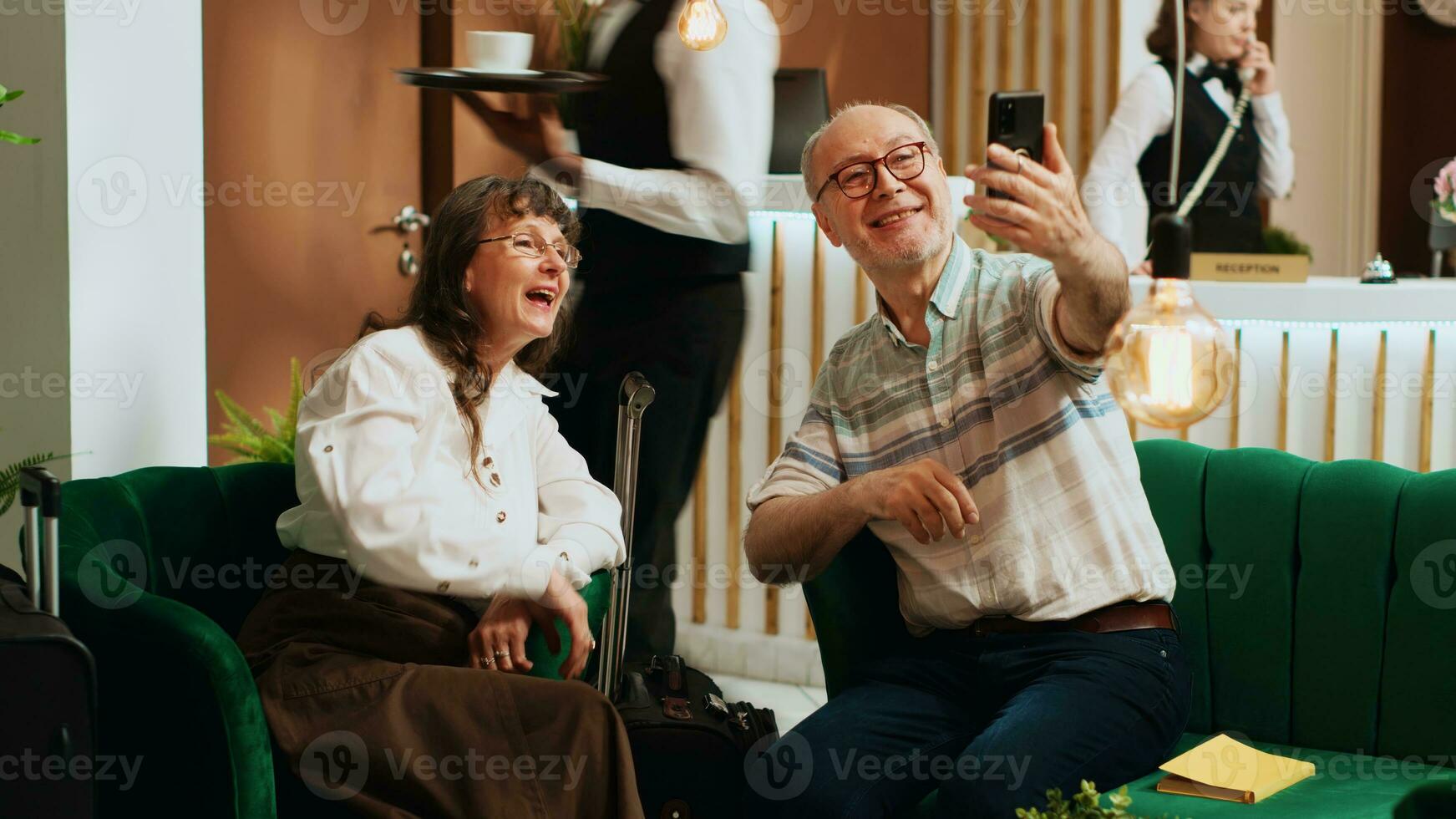 Elderly tourists using videocall connection to keep in touch with family members, travelling together on retirement trip. Husband and wife talking to children on teleconference call. Tripod shot. photo