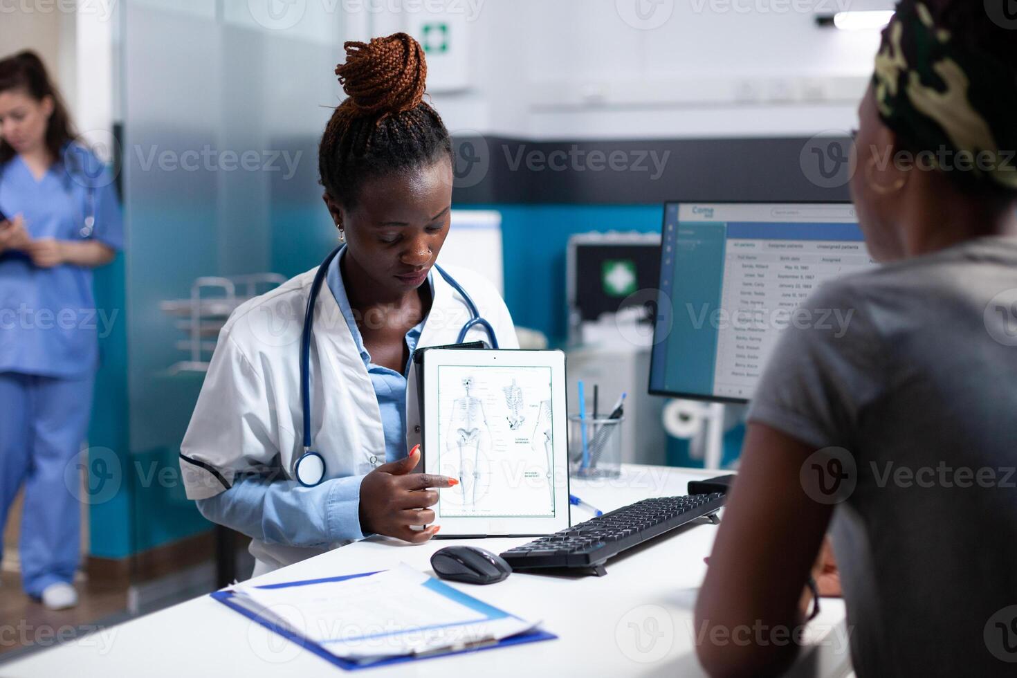 Bone doctor at physical examination offering informations to patient on tablet using human skeleton figure. Orthopedic specialist providing healthcare diagnosis to woman at appointment checkup photo