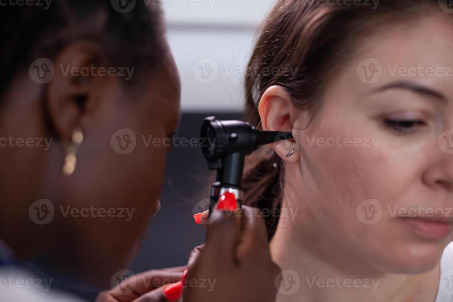 Otorhinolaryngologist in audiology hearing ear medical exam treating patient earache pain and infectious disease of ear canal. Doctor using otoscope during medical checkup in hospital. Close up. photo