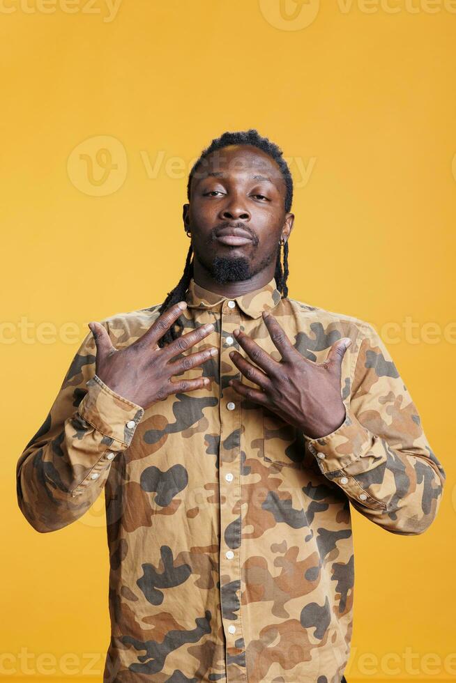 Zen young adult taking deep breaths, meditating in studio over yellow background. Peaceful african american relaxing body muscles during peaceful activity, enjoying practicing healthy lifestyle photo