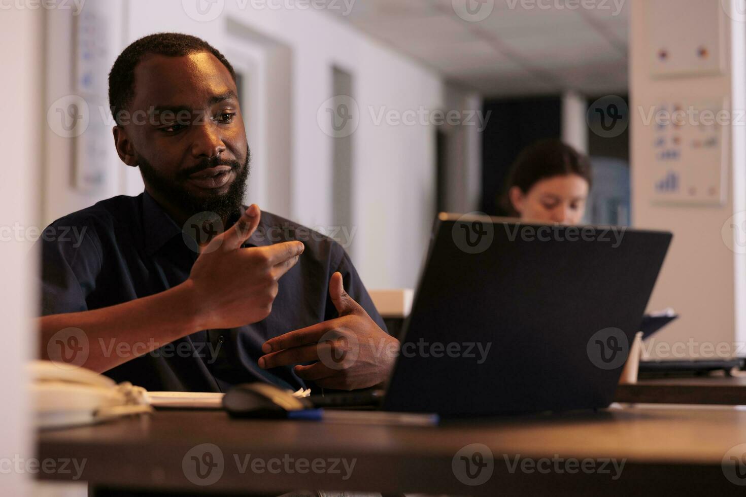 proyecto gerente que se discute empresa estrategia plan en video conferencia con compañero de trabajo, corporativo trabajador respondiendo Internet llamada en oficina a noche. africano americano hombre utilizando videollamada computadora software foto