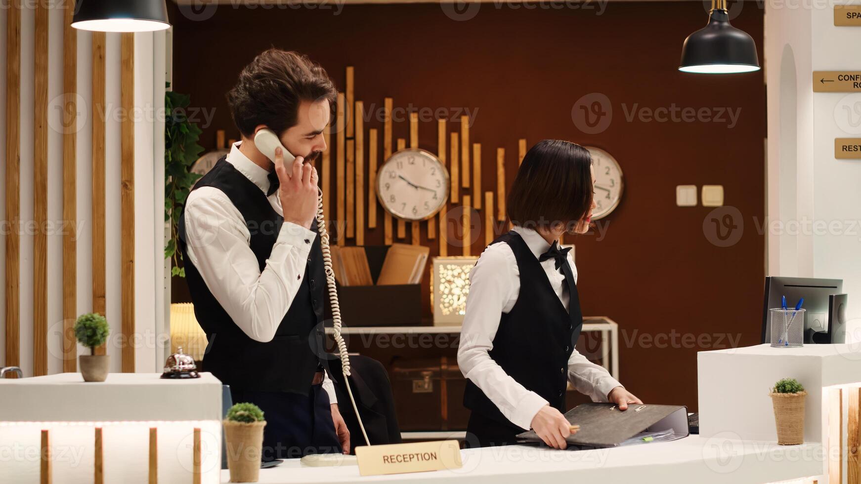 Teamworking professional hotel personnel checking tourists reservation date at check in reception desk. Receptionists coworkers discussing incoming guests booking informations photo