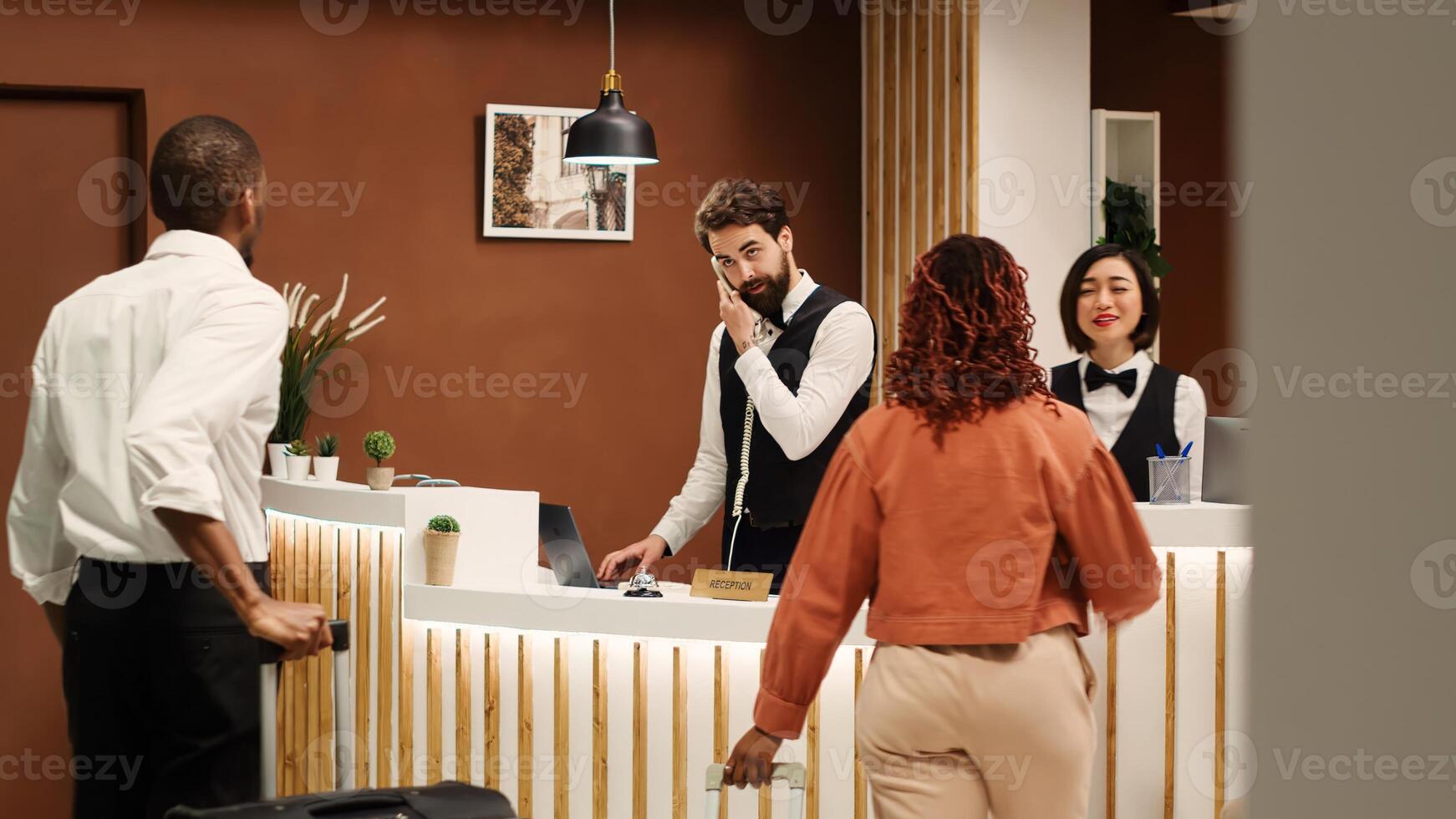 Professional concierge personnel welcoming tourists at reception desk during check in process. Elegant friendly receptionist team greeting vacation trip guests in hotel lobby photo
