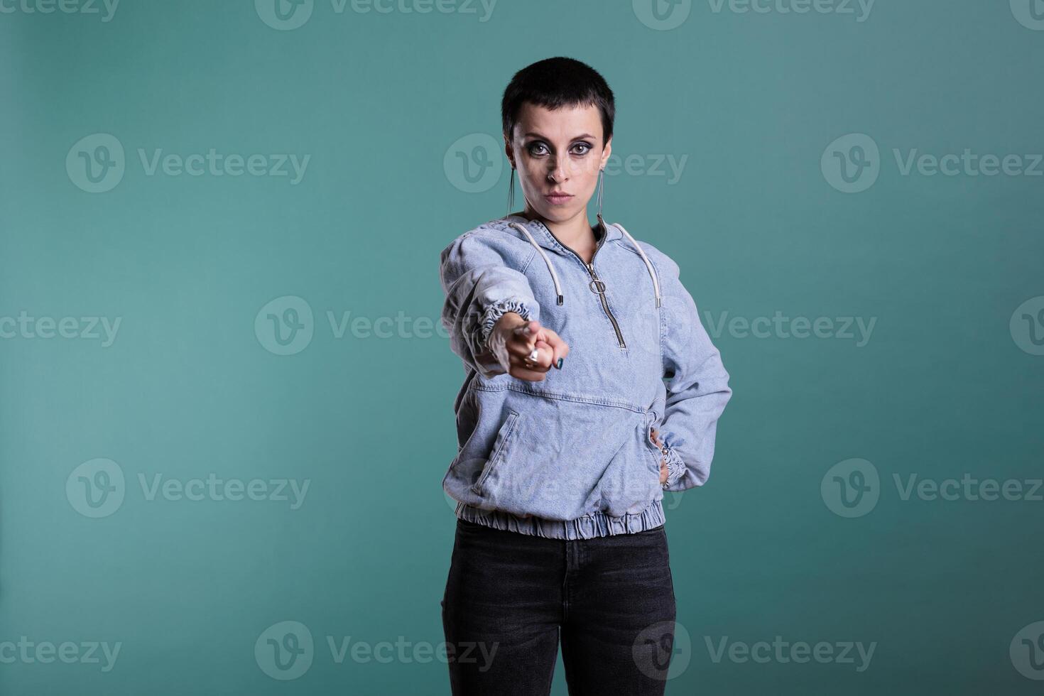 Displeased angry woman pointing index finger in front of camera screming during studio shot on isolated background. Upset nervous female having mental breakdown, disappointment expression photo