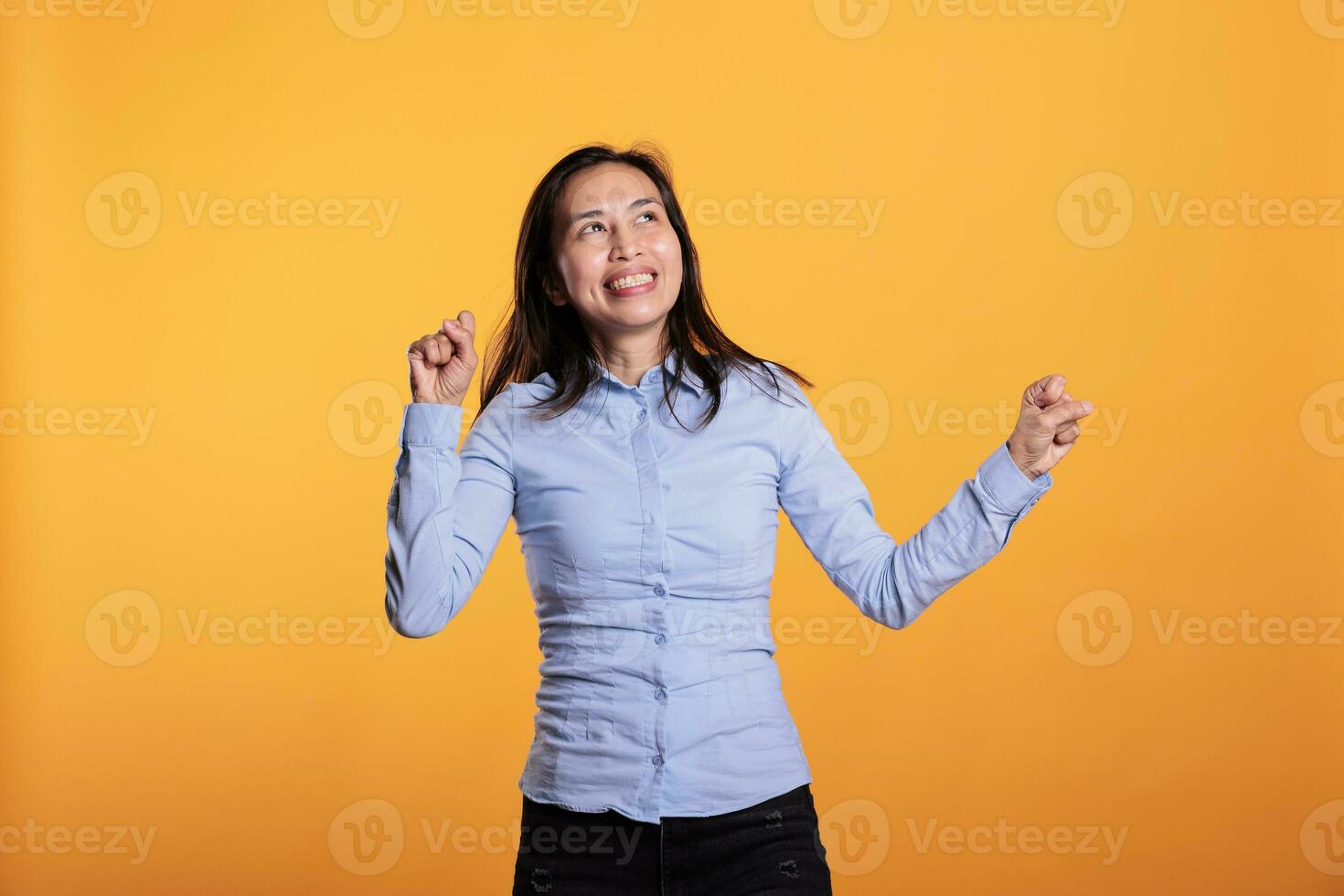 Cheerful filipino woman dancing and having fun during leisure time in studio over isolated background. Joyful smiling model enjoying showing her dance moves during work break. Entertainment concept photo