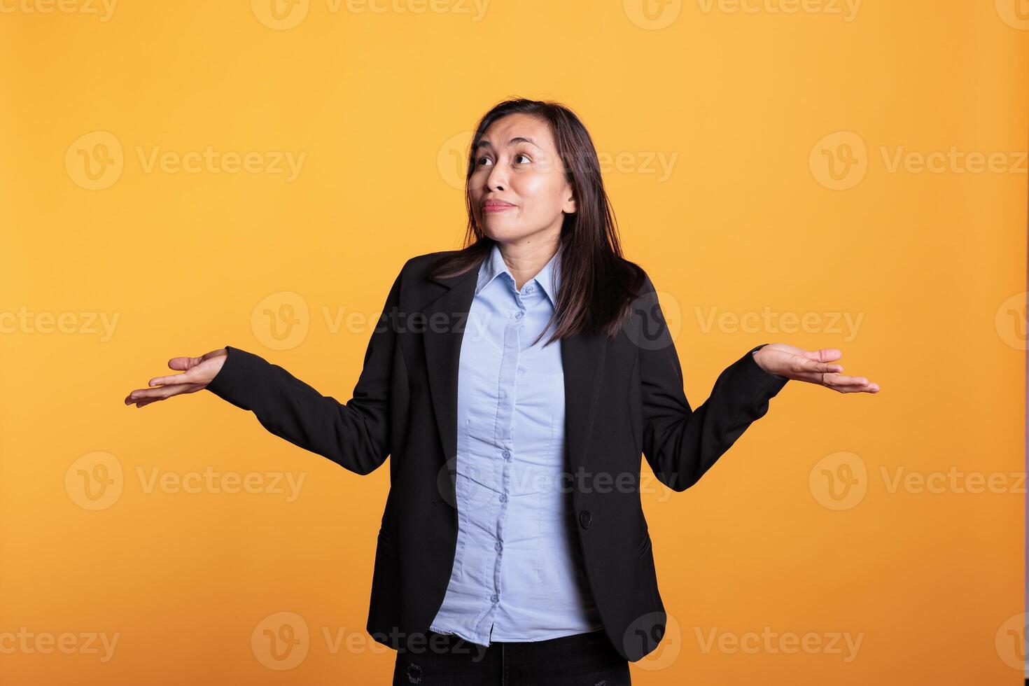Confused woman shrugging shoulders in studio, doing i dont know sign, having doubtful facial expression. Uninterested filipino model feeling clueless and puzzled about question answer. photo