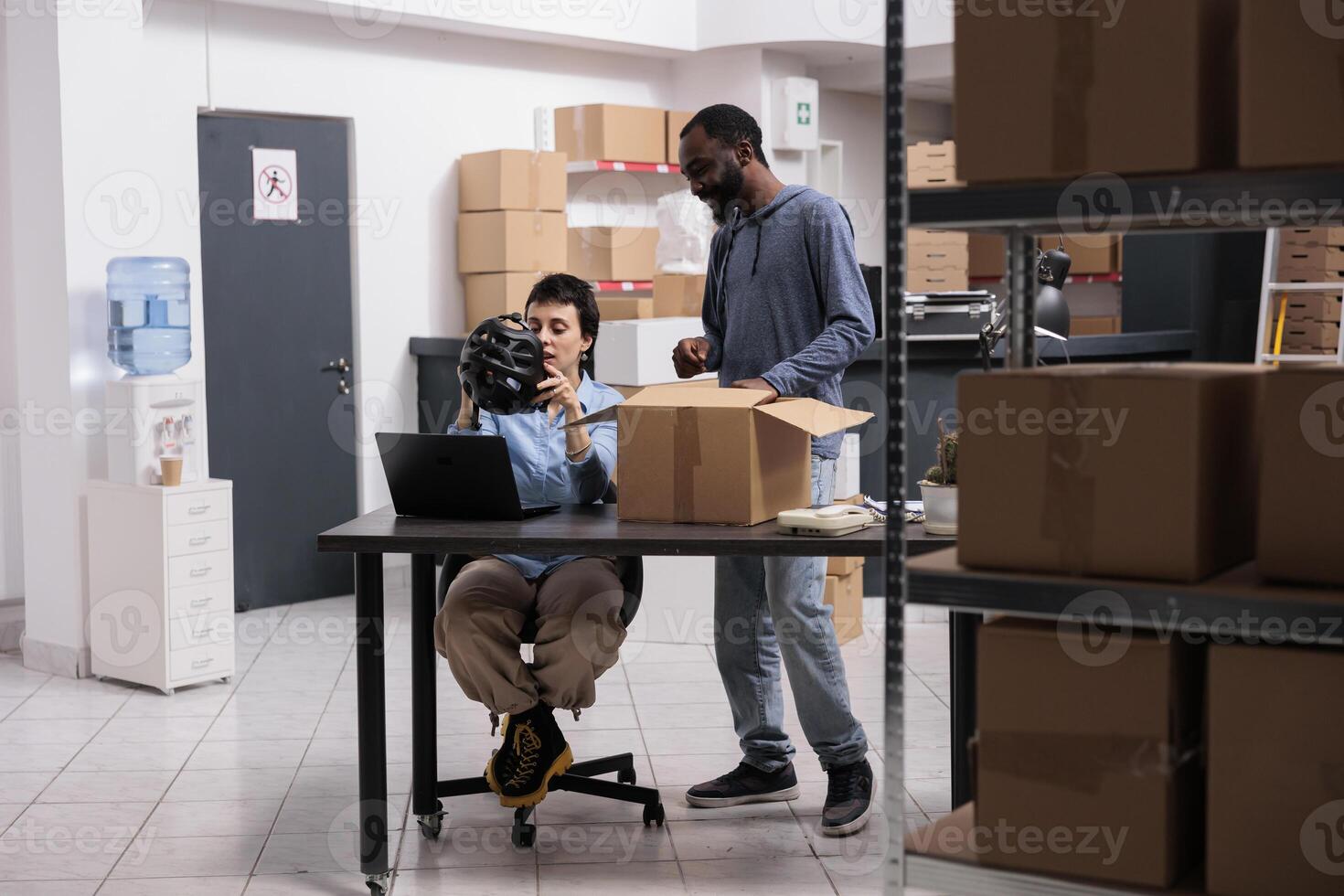 Warehouse employees checking customer helmet order before preparing product for delivery while discussing shipping detalies. Manager and supervisor working in delivery department in warehouse photo