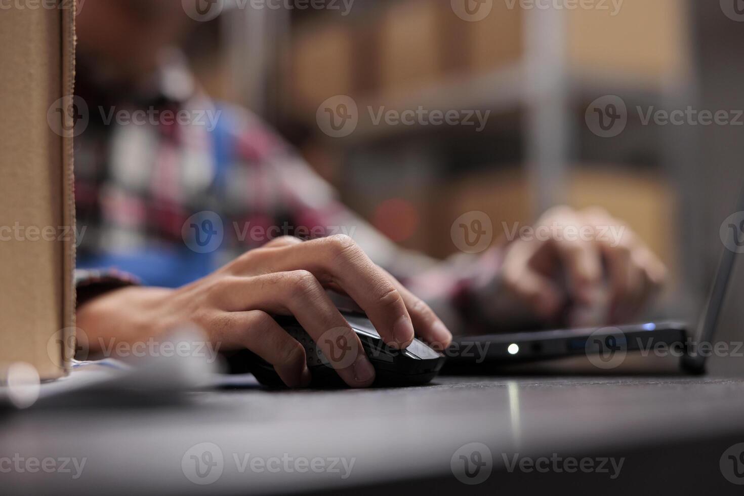 Postal warehouse employee checking delivery customer satisfaction on laptop. Post office storehouse worker managing shipping operations while using computer mouse close up photo