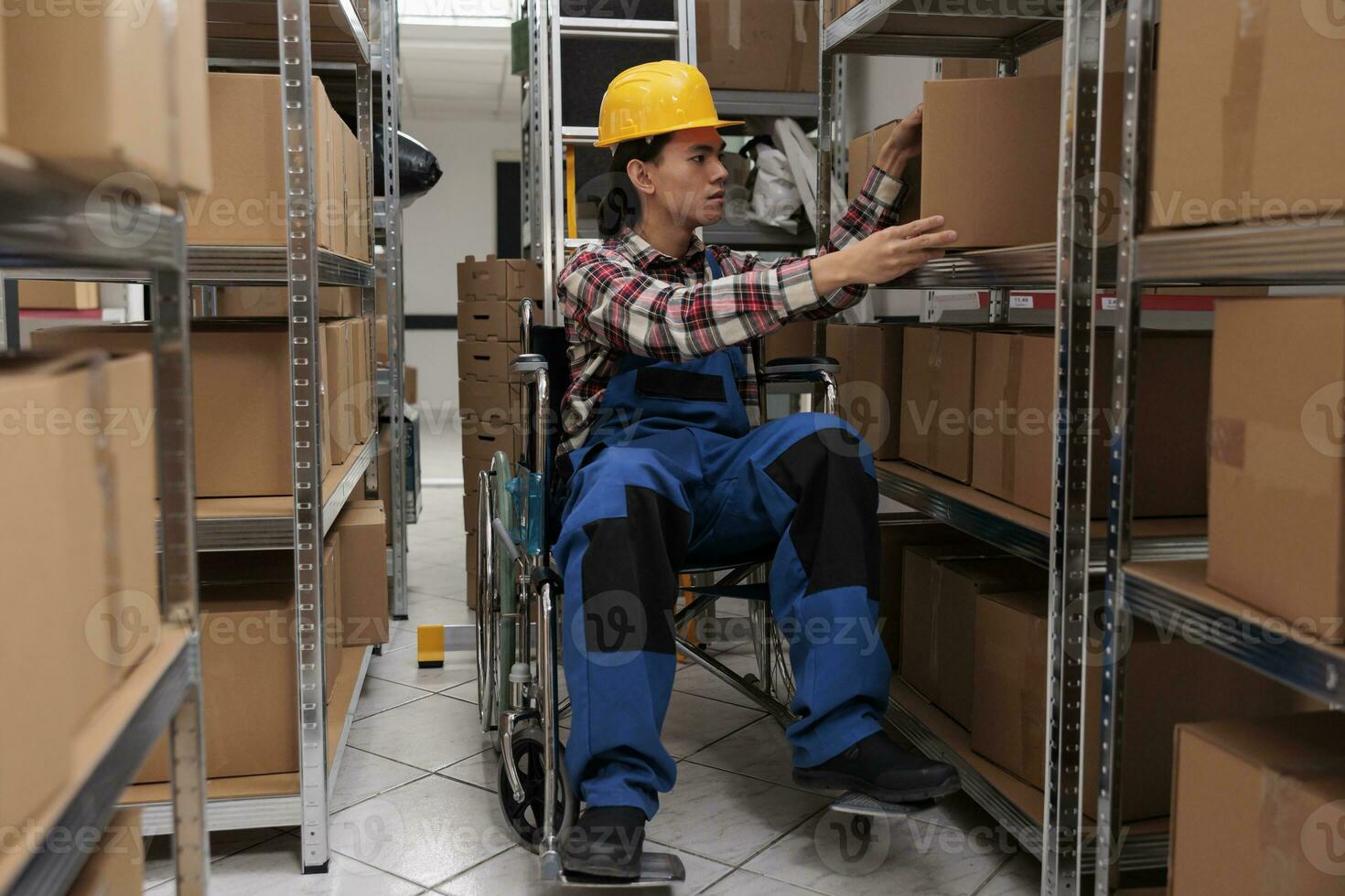 joven asiático almacén trabajador en silla de ruedas tomando paquete o empaquetar desde estante. almacén orden recogedor con físico invalidez buscando cartulina caja mientras trabajando en almacenamiento habitación foto