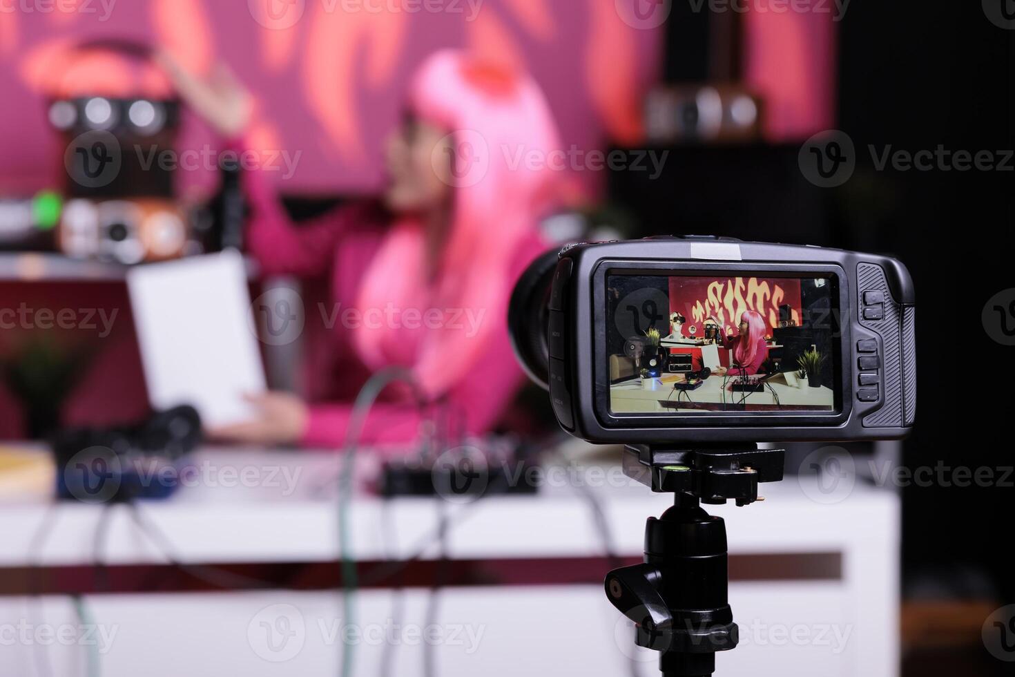 Vlogger holding white box reviewing product in front of camera while recording podcast in vlogging studio. Content creator woman filming vlog using professional broadcasting equipment photo