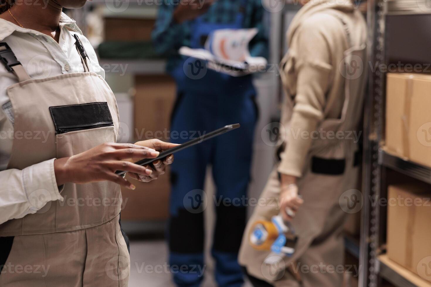 Distribution department worker recording and maintaining inventory in digital tablet application in warehouse. Storehouse manager coordinating parcels delivery and dispatching on portable gadget photo