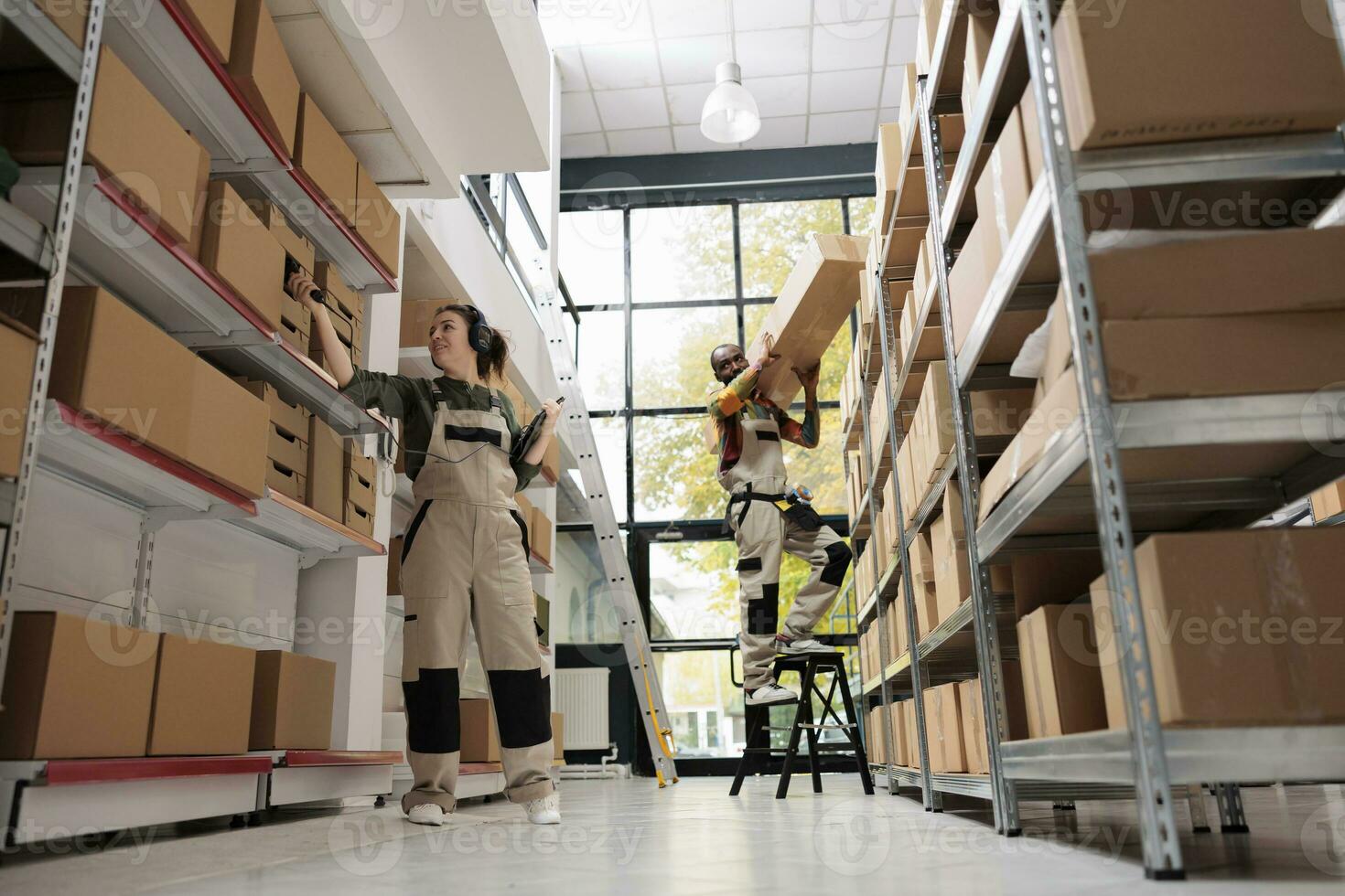 Storage room worker scanning products barcode using store scanner, checking cardboard box details during warehouse inventory. Supervisor listening music while preparing customers orders photo