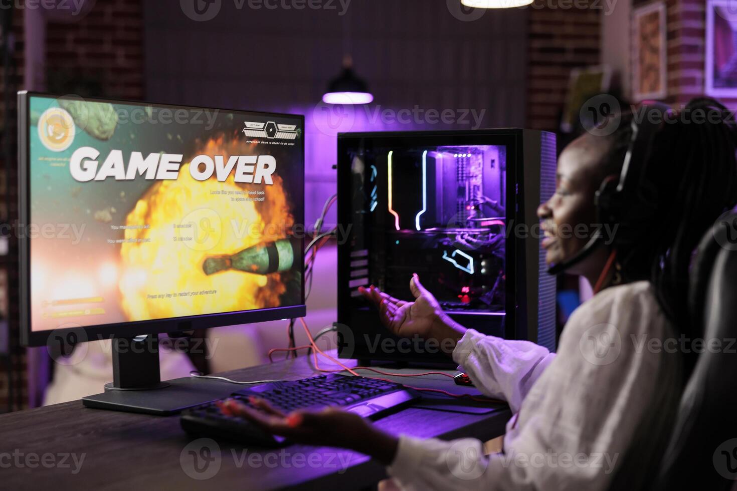 Gamer feeling irked after losing singleplayer action videogame mission, being outsmarted by enemies. African american woman confused after seeing game over screen on gaming computer photo