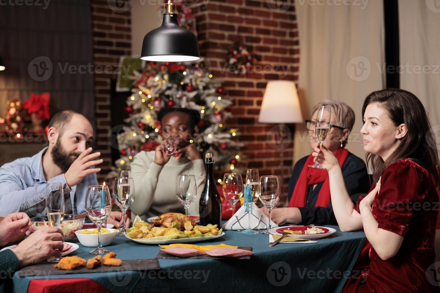 Family raising wine glasses for toast during festive dinner, enjoying holiday time at home with traditional meal. Diverse people giving speech to thank everyone for gathering around the table. photo