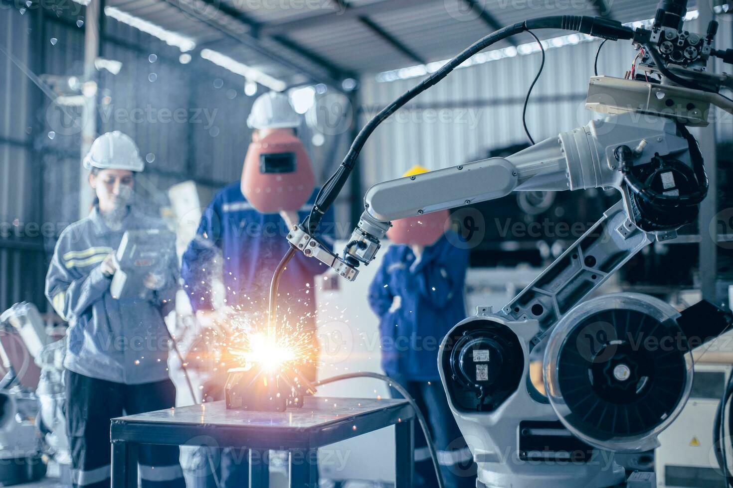 Engineer worker team working control operate small  robot welding arm in metal workshop photo