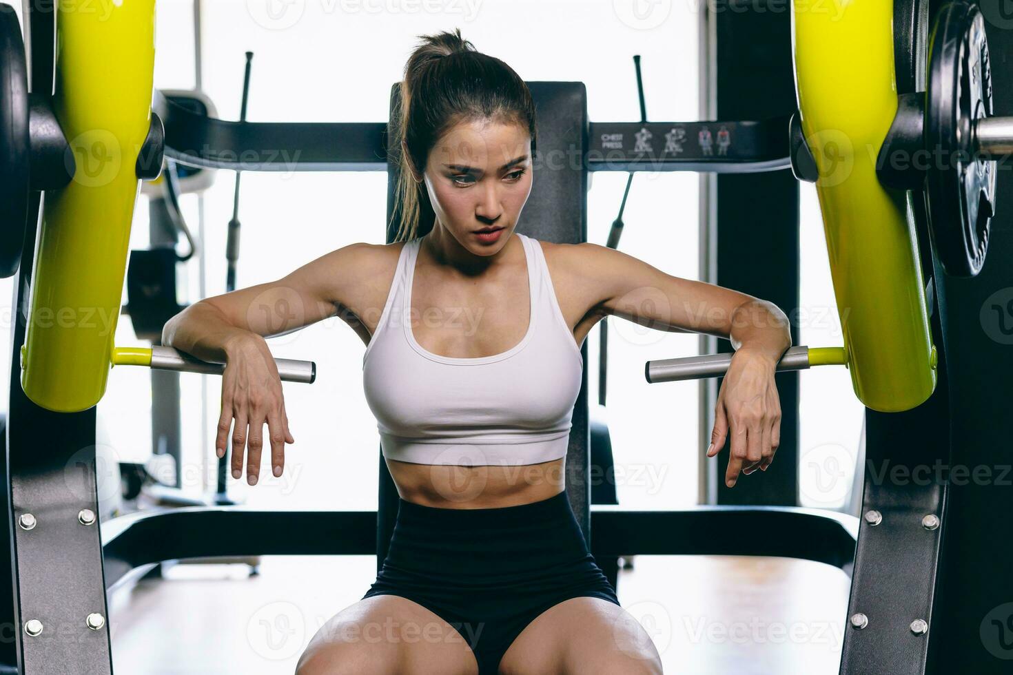 hermosa modelo de asiático mujer deporte sano Delgado formación construir músculo con peso máquina en gimnasio aptitud deporte club foto