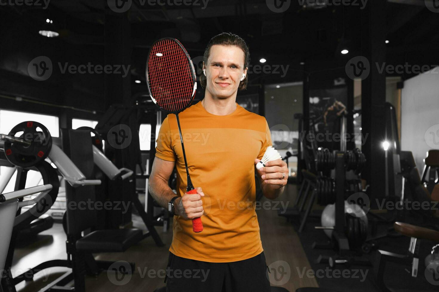 smart professional badminton player with racket and feather shuttlecock standing portrait in gym sport club muscle fitness training photo