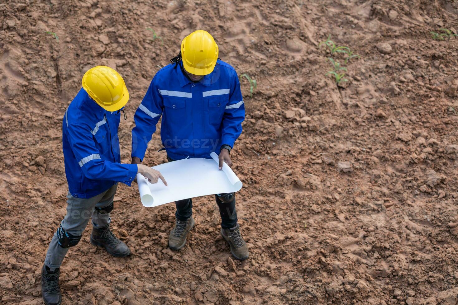 Land surveyor team standing working together at construction field consult study looking building location with floor plan photo