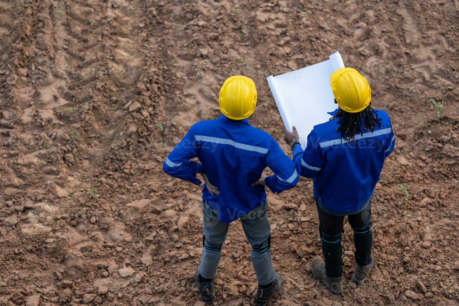 Land surveyor team standing working together at construction field consult study looking building location with floor plan photo