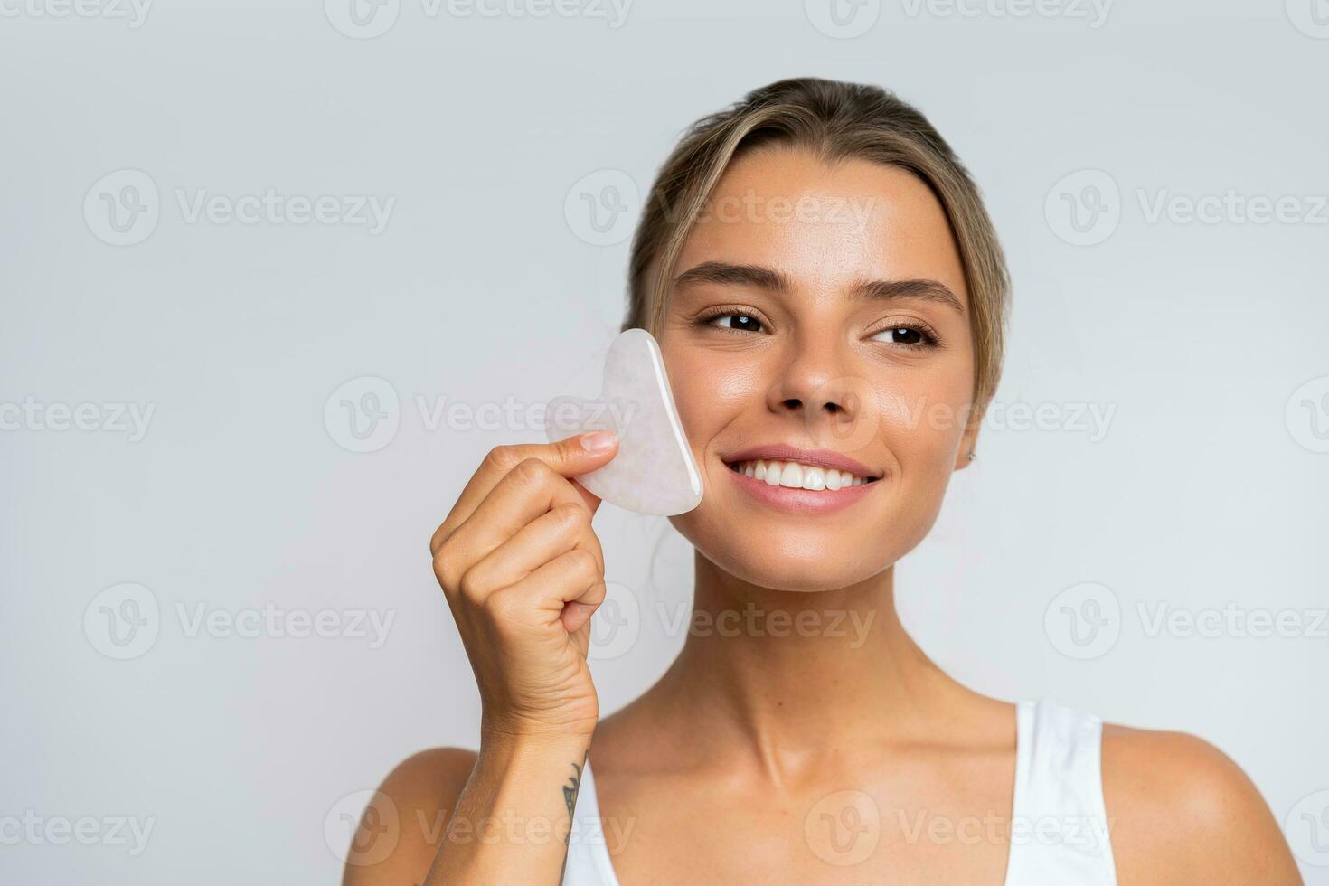 Face massage. Portrait of  beautiful  female fashion model isolated on  white studio background. Blond caucasian woman with healthy well-kept skin. Style and beauty, skin care concept. photo