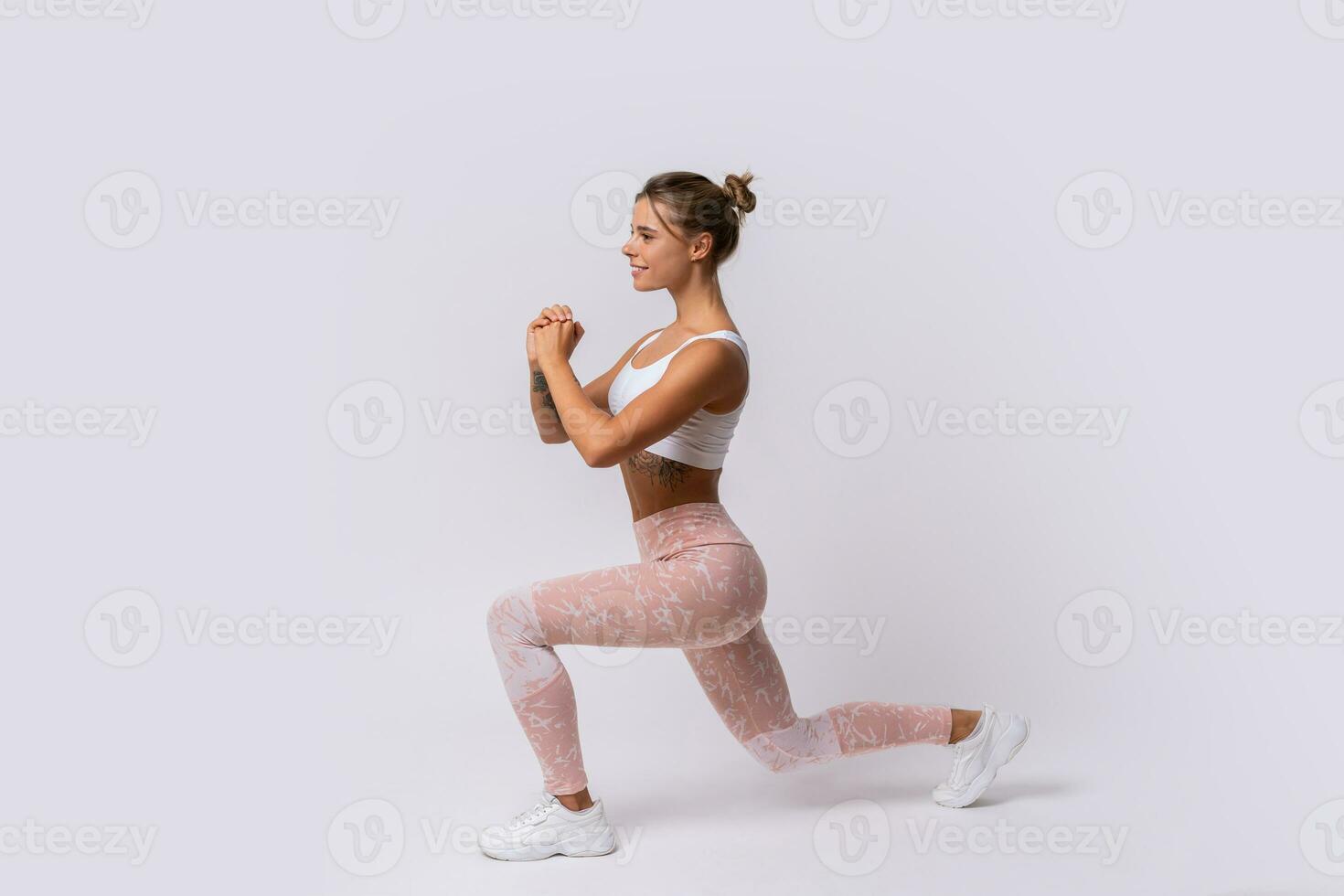Athletic   blond woman with perfect smile training muscles of hands and legs. Photo of woman in stylish sportswear isolated on white background.