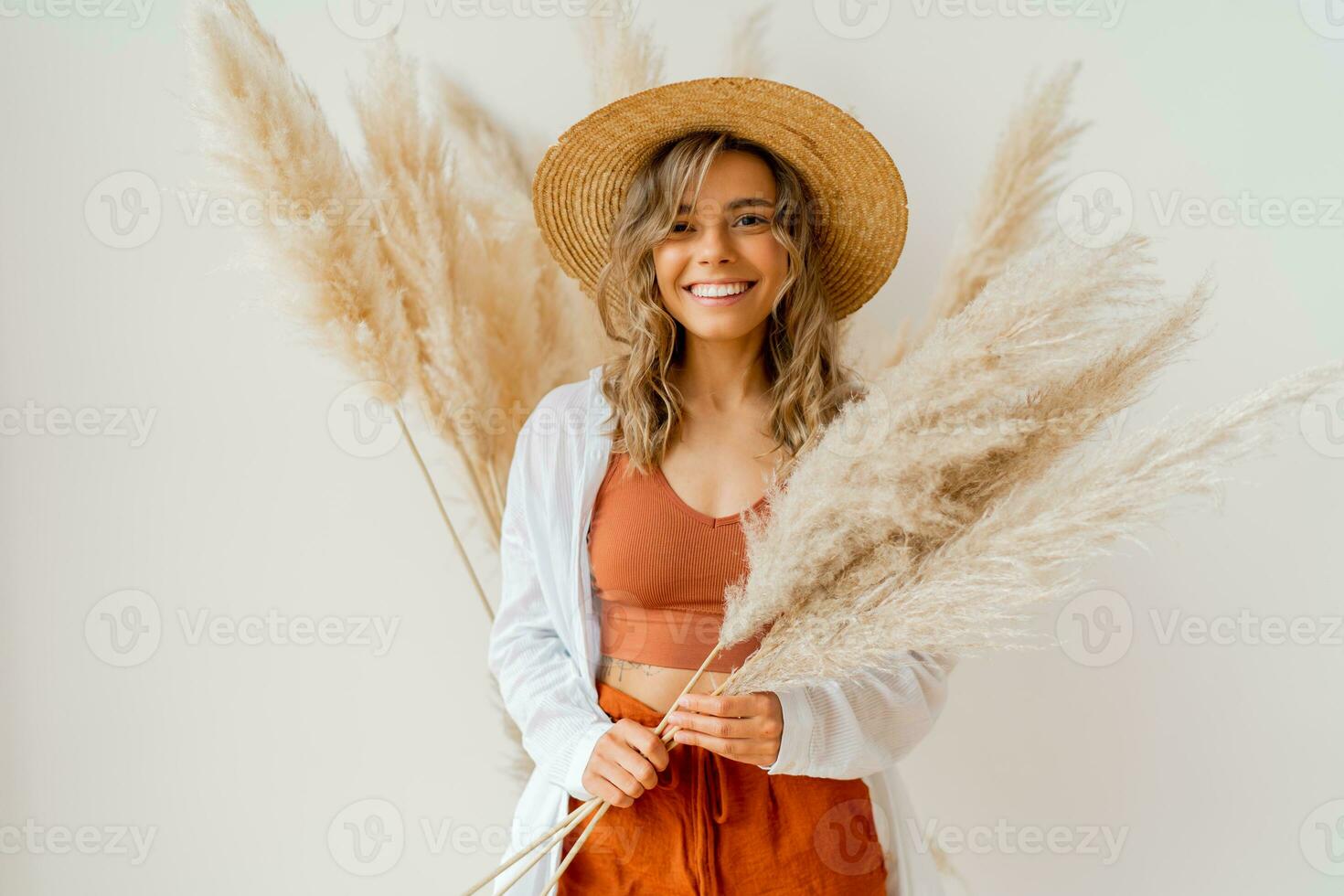 Close up portrait of smiling  blond woman with perfect smile in stylish boho autfit. Posing in inerior studio over white background. photo