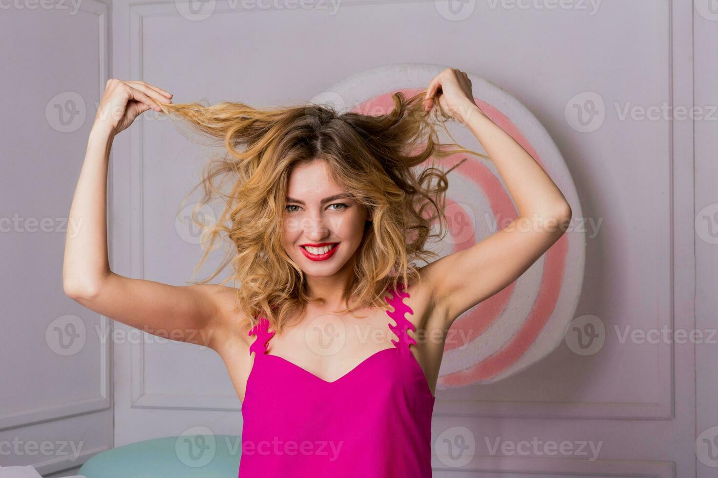 Stylish elegant blonde woman posing in studio with sweets in  pink dress. Candy  and macaroons objects  background. photo