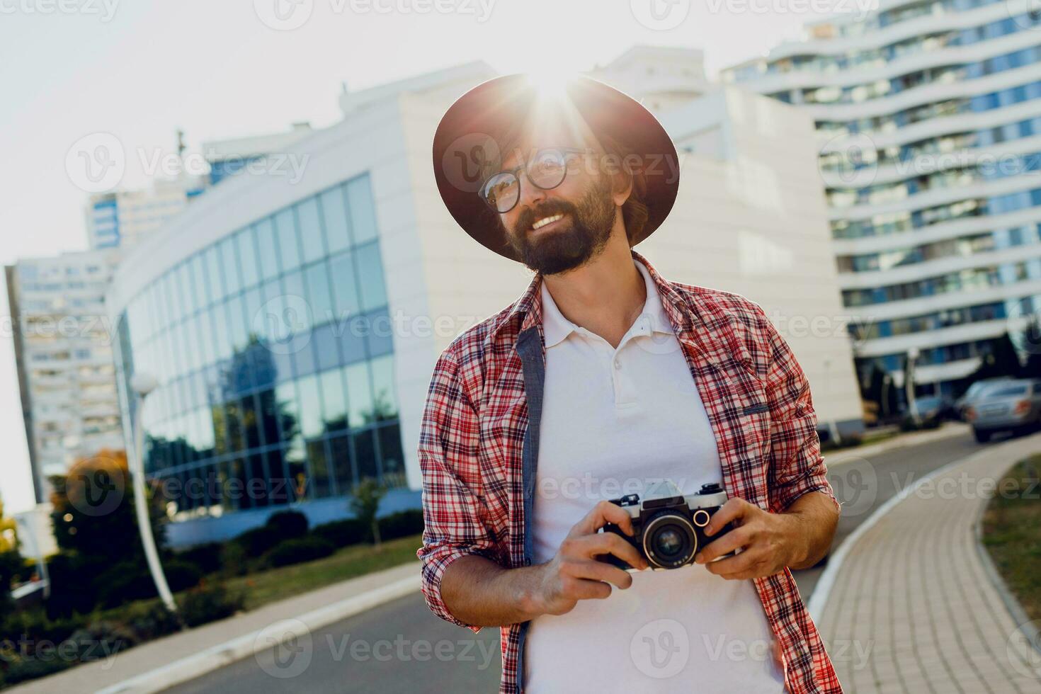 Fashionable  beard man portrait, using retro film photo camera  , making  photos .  Hipster style. Wearing black hat, stylish eyeglasses, checkered shirt .