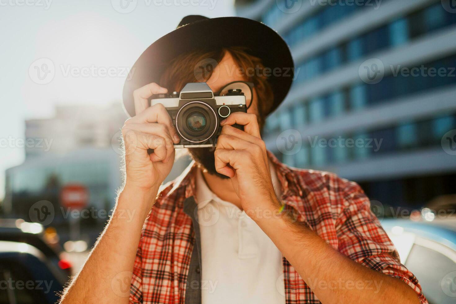 Fashionable  beard man portrait, using retro film photo camera  , making  photos .  Hipster style. Wearing black hat, stylish eyeglasses, checkered shirt .