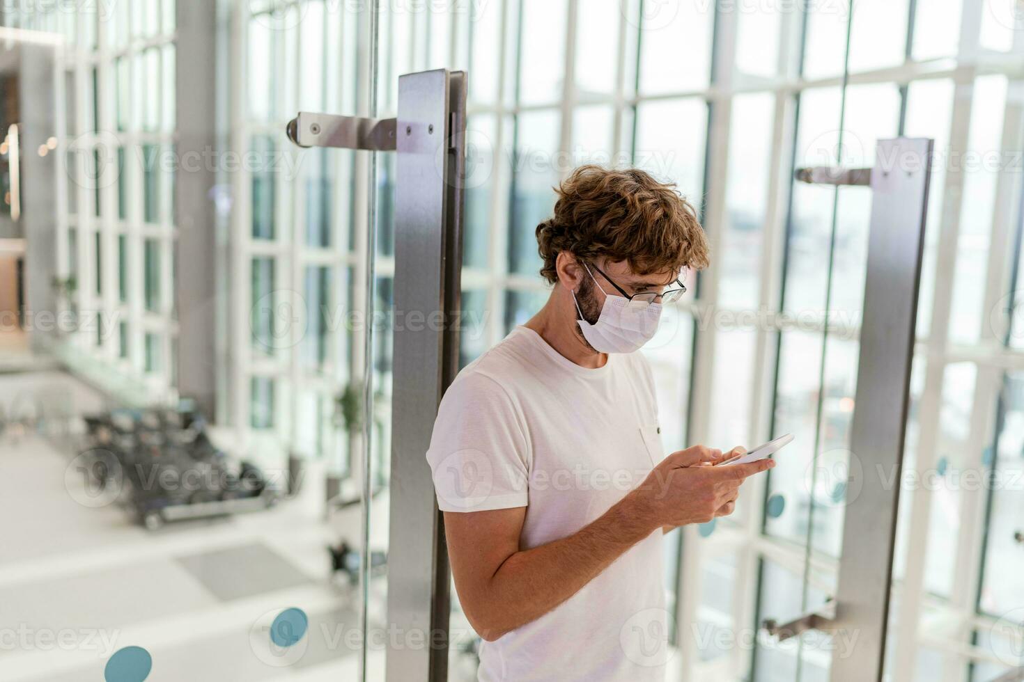 Man wearing face mask  in airport and   using smartphone . Health and travel concepts during coronavirus pandemic. photo