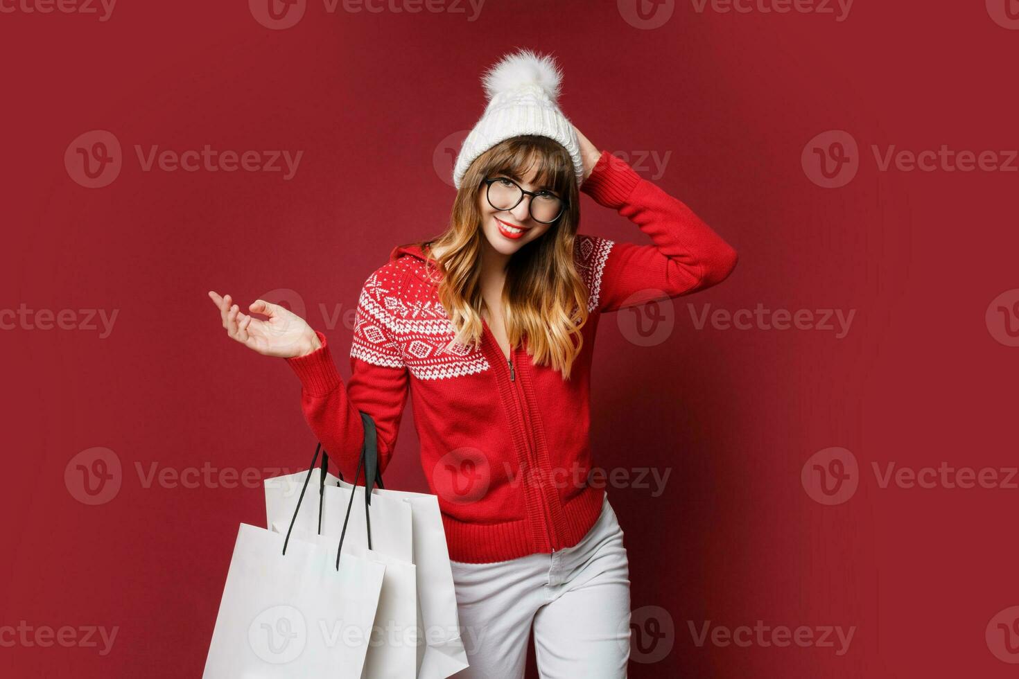 sonriente mujer en invierno atuendo posando en estudio en rojo antecedentes. foto