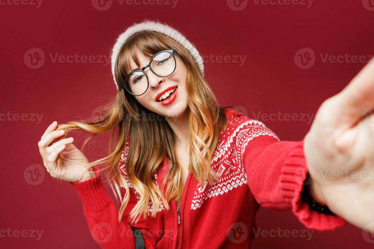 sonriente mujer en invierno atuendo posando en estudio en rojo antecedentes. foto