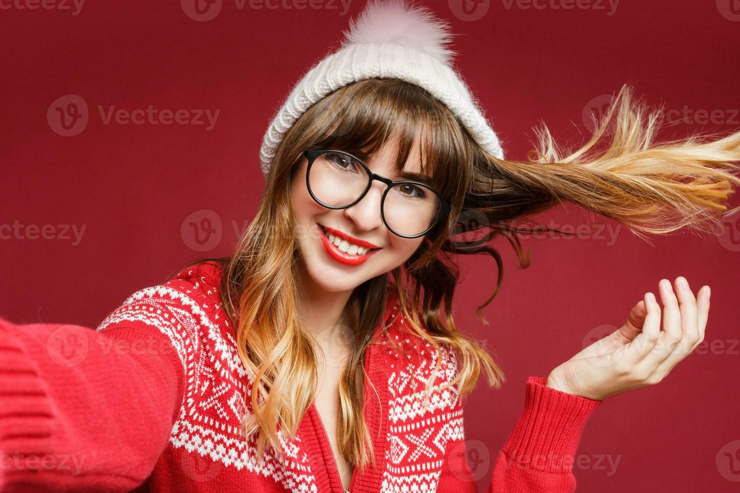 Smiling woman in winter outfit posing in studio on red background. photo
