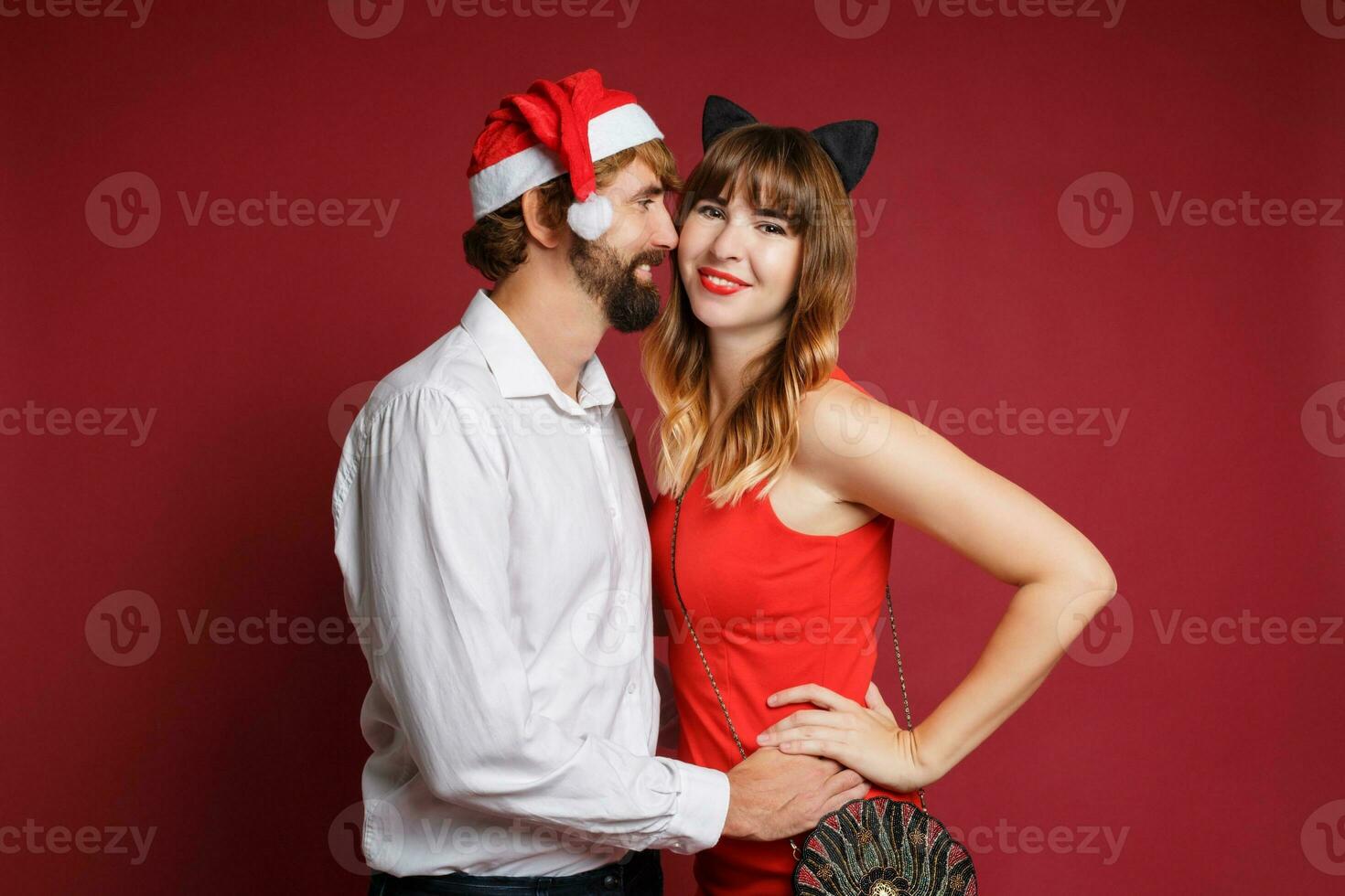 Elegant couple in love posing on red background in fashionable elegant outfit.  New Year mood photo