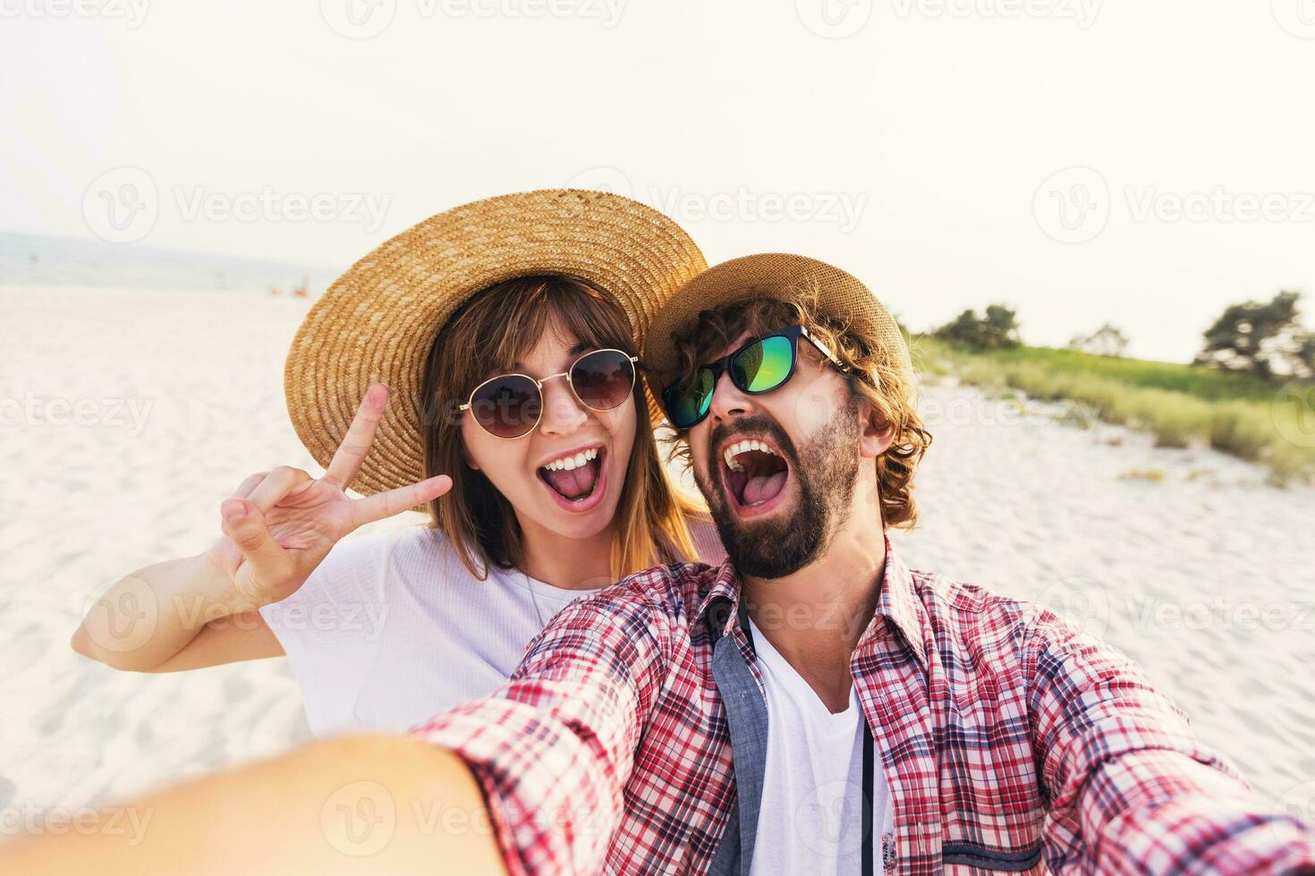 Couple or best friends man and woman having fun on summer sunny beach . Wearing straw hat, sunglasses, stylish  shirts . photo