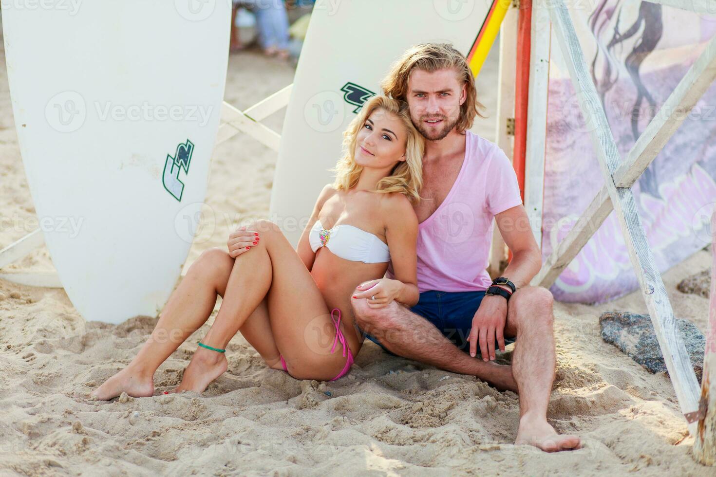 Beautiful blonde woman and handsome man ,   posing on the tropical summer beach surfer background. photo