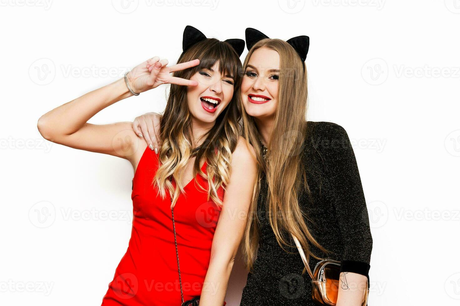 Two pretty women  in cat carnival ears , evening dress having fun on  white isolate background. Friends celebrating  new year or birthday party. photo
