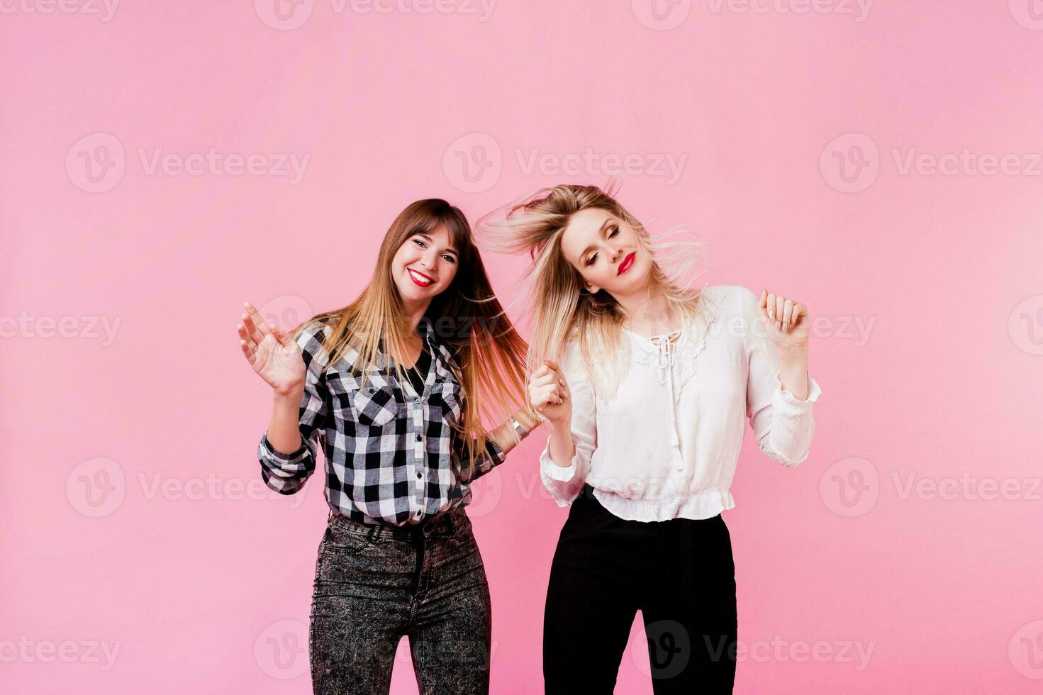 Two carefree female having fun and dancing on pink background. Flash portrait. Party mood . Friendship concept. photo