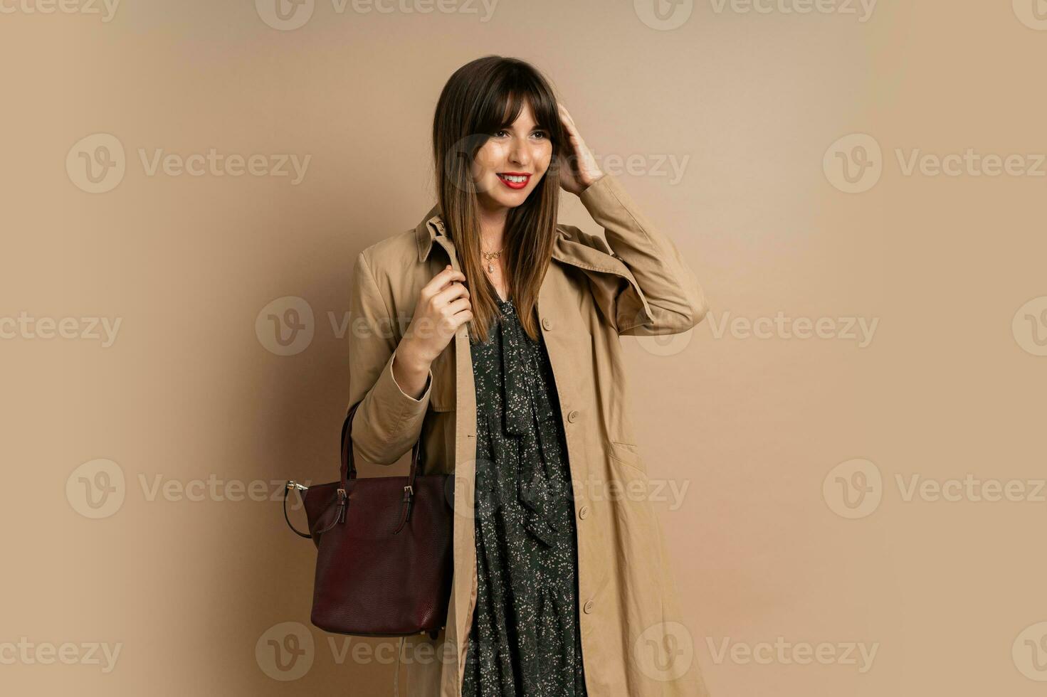 Stylish brunette woman  wearing trendy coat  , posing over beige background.  Winter fashion trends. photo