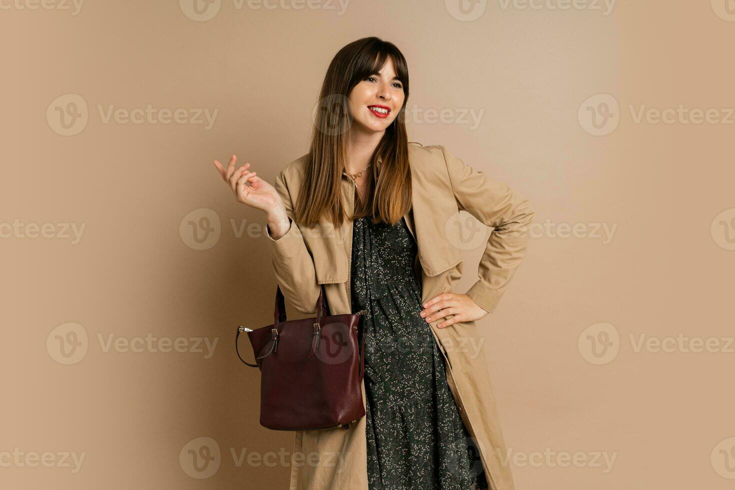 Stylish brunette woman  wearing trendy coat  , posing over beige background.  Winter fashion trends. photo